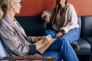 Terapeutka robiąca notatki podczas sesji terapeutycznej z klientką.